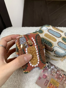 Close-up of retro woven coin purse with colorful wave pattern and gold heart zipper pull