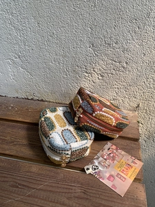 Macro detail of tweed coin purses featuring retro patterns and golden heart zippers