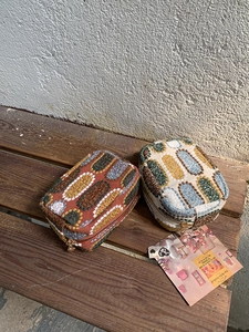 Detailed embroidery texture on mini pouches with heart-shaped metal zippers on wood