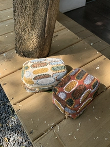 Outdoor shot of two embroidered mini canvas pouches with zippers on a wooden bench