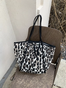 Quilted leopard print tote bag with black strap handles on a vintage wooden chair
