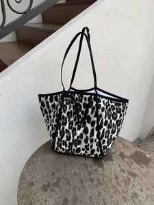 Detail of leopard print quilted tote bag with black strap on a wooden stool