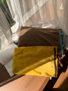 Detail of lightweight nylon travel storage bags in brown and yellow on a wooden table