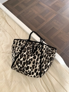 Quilted leopard print tote bag with large capacity and black handles in a home setting