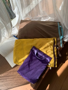 Three colorful nylon travel storage pouches on a wooden surface with natural light