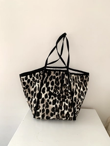 Close-up of leopard print tote bag featuring quilted texture and black woven straps