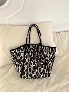 Detail of leopard print quilted tote bag with black strap on a white bedding background