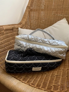 Detail of heart-quilted travel organizer bags in metallic silver and classic black colors