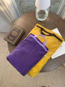 Detail of ultralight nylon storage bags in yellow and purple on a wooden table
