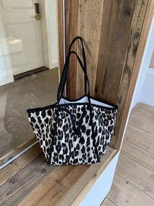 Macro view of leopard print quilted tote bag featuring black woven strap and large opening