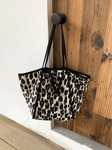Detail of leopard print quilted tote bag with stitching texture and black straps