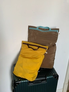 Close-up of lightweight nylon travel organizers with handles on a green suitcase