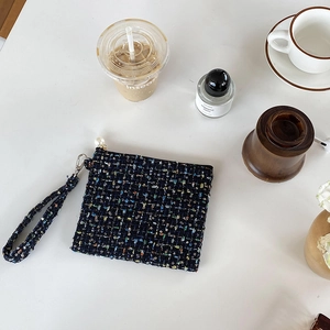 Detail van zwarte tweed make-uptas met grote parelrits en handige polsband