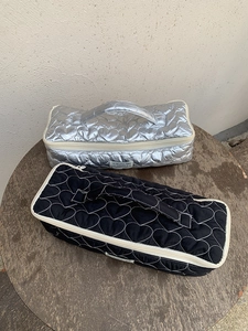 Quilted heart texture cosmetic bags in silver and black on a wooden table surface