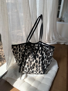 Close-up of leopard print quilted tote bag with black strap in a bright sunlit interior