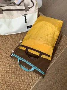 Macro detail of waterproof nylon packing cubes in yellow and brown with sturdy handles