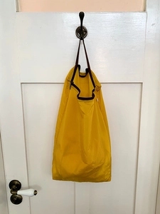 Hanging yellow waterproof nylon travel storage bag with brown handle on white door hook