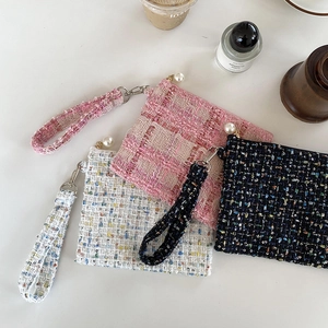 Detail van mini make-up tasjes van tweed met parelrits in roze, wit en zwarte kleuren