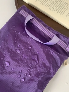 Close-up of waterproof purple travel storage bag with hydrophobic water droplets