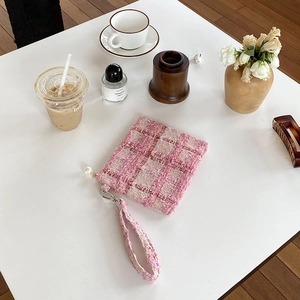 Chique roze tweed make-up tas met polsbandje en parel detail op een witte tafel