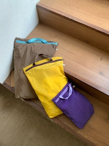 Three assorted travel storage bags in brown, yellow and purple on wooden stairs