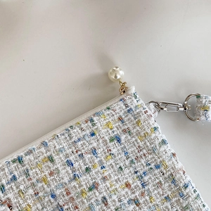 Detail van tweed make-up tasje met grote parelritssluiting en zilverkleurige metalen haken