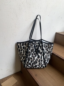 Leopard print quilted tote bag with black straps on wooden staircase display