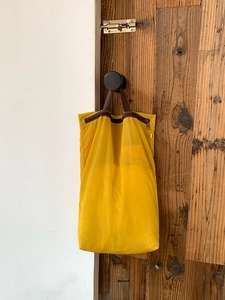 Detail of yellow mesh travel organizer bag hanging on a hook for luggage storage