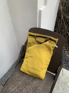 Close-up of yellow nylon travel organizer bag with handle on a wooden chair