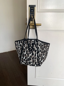 Detailed macro view of leopard print tote bag featuring quilted texture and black strap