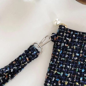 Detail van de tweed make-uptas met lovertjes, zilveren sluiting en witte parel ritstrekker