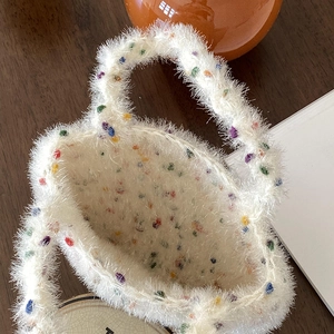 Sac à main blanc en peluche douce avec pois colorés dans un cadre de vie chaleureux