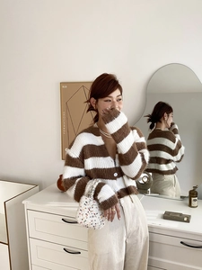 Détail d'un gilet en maille rayé marron et blanc avec texture peluche et col en V