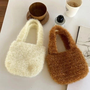 Gros plan de mini sacs à main en peluche tressée blanc cassé et caramel sur table blanche