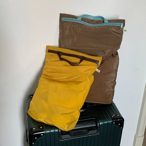 Ultralight waterproof travel organizers in yellow and brown on top of a suitcase