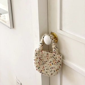 Mini sac à main en peluche blanche avec pois colorés suspendu à une porte