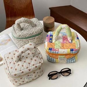 Three quilted floral and strawberry cosmetic bags displayed with vintage lifestyle props
