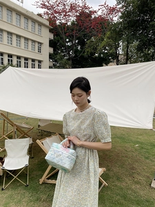 Quilted floral handbag with tie-dye pattern and white label shown in outdoor setting
