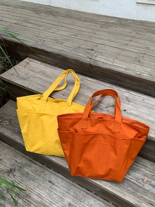 Dettaglio di borse tote in nylon colorate con tasche multiple su legno