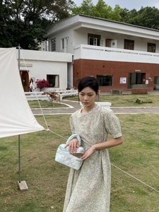 Outdoor shot of a quilted tie-dye makeup bag with floral summer dress on a lawn