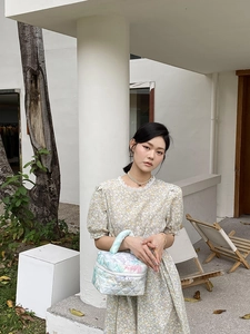 Outdoor model display of a floral quilted makeup bag and retro puff sleeve dress