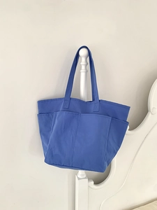 Dettaglio della borsa tote in tela blu che mostra tre grandi tasche frontali utili