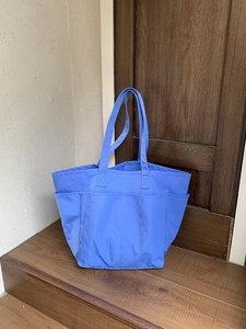 Dettaglio della borsa tote in nylon celeste con molteplici tasche frontali funzionali