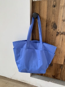 Dettaglio borsa tote in nylon azzurro con tasche esterne multiple e tracolla larga