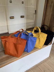 Dettaglio delle borse tote in nylon con tasche nei colori arancione, blu, giallo e nero