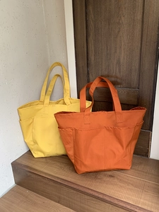 Dettaglio delle borse tote in nylon giallo senape e arancione con tasche multiple