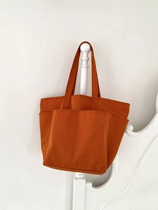 Dettaglio della borsa tote in nylon marrone con tasche anteriori funzionali e tracolla