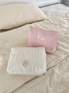 Detail of quilted nylon travel pouches in soft pink and cream with a secure zipper closure