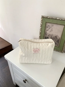 Close-up of beige pleated nylon storage bag with stylish woven label and zip closure