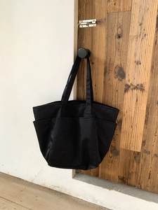 Dettaglio della borsa tote in nylon nero con tasche multiple e doppie cinghie per le spalle